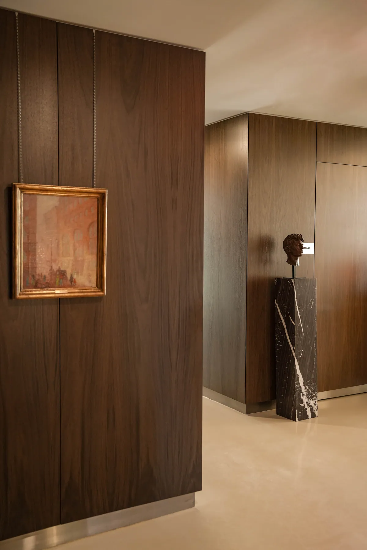 The lobby of the Beverly Hills dental office of Kiyan Mehdizadeh, DMD, with a walnut wall and a bust on a pedestal